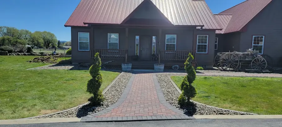 Red-brick paver walkway with a charcoal border leading to a ranch house