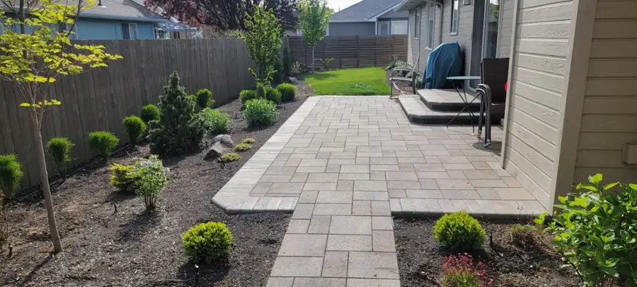 Paver walkway running between planted beds to the back lawn